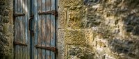 Weathered wooden shutters with rusty hinges on ancient stone wall showcase rustic Mediterranean architecture and vintage charm for home decor projects.