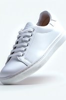 Clean white leather sneaker with laces on light background, minimalist design and classic silhouette, isolated product shot for fashion and footwear marketing.