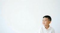 Young Asian male wearing white casual shirt against neutral background, looking to the side with thoughtful expression, suitable for corporate, lifestyle, and business applications.