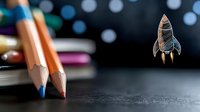 Colorful pencils on dark background with creative rocket sketch overlay, representing education, imagination and creative startup concept for business growth.