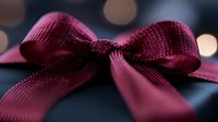 Elegant burgundy satin ribbon bow with soft bokeh lights in background, macro close-up shot showing detailed textile texture and festive holiday mood.