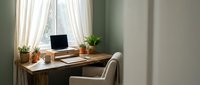 Cozy home office workspace with laptop computer on wooden desk by window with natural light, comfortable chair and green plants for productive remote work environment.