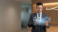Caucasian male professional businessman in dark suit and tie holding transparent digital tablet with glowing network interface in modern office environment for corporate technology concepts.