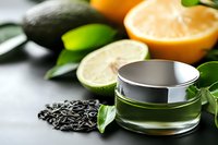 Green cosmetic cream jar with citrus fruits and tea leaves on gray background, natural organic skincare product for beauty and wellness spa treatments.
