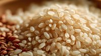 Close-up of raw brown rice grains with warm lighting, showcasing natural texture and varying shades from light beige to darker brown for culinary and food photography use.
