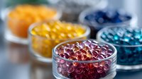 Colorful bath oil pearls in glass bowls arranged in rainbow order. Transparent gel capsules for aromatherapy, spa treatments and cosmetic purposes on light background.
