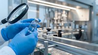 Laboratory scientist in blue gloves examining sample with magnifying glass in sterile research facility for quality control and scientific analysis.