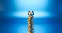 Piggy bank balancing on stack of golden coins against blue background representing savings growth and financial planning for future investments.