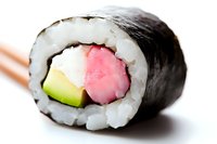 Fresh sushi roll with crab meat, avocado and rice wrapped in nori seaweed, close-up on white background showing vibrant ingredients and texture.