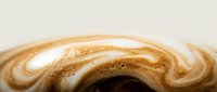 Creamy coffee beverage with latte art foam design and swirled caramel pattern, suitable for cafe menus and beverage marketing.