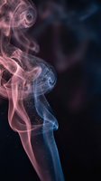 Colorful smoke swirls with pink and blue hues creating ethereal patterns against dark background for artistic design projects.