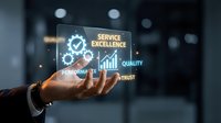 Businessman hand holding glowing holographic display showing service excellence with gears, quality, performance, and trust icons in modern office environment.