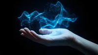 Digital blue energy particles flowing above open palm creating magical holographic effect on dark background for technology and innovation concepts.