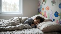 Young child sleeping peacefully in cozy bedroom with colorful ocean-themed wall decals featuring fish and sea creatures for kids room design and decor.