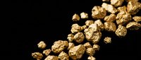 Golden nuggets scattered on dark background representing precious metal mining wealth and luxury investment opportunities.
