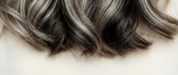Luxurious wavy hair with silver highlights and dark brown lowlights showcasing modern hair coloring techniques for salon and beauty industry use.