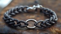 Black braided leather bracelet with silver metal clasp and ring detail on rustic wooden surface for fashion accessories and jewelry design projects.