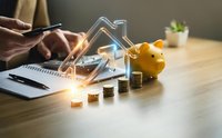 Real estate investment planning with piggy bank savings and house model on wooden desk for mortgage loan calculation and property purchase budget.