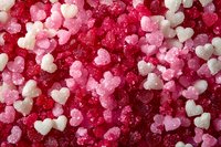 Small heart-shaped sugar crystals in shades of pink, red and white creating romantic pattern background for Valentine's Day and love-themed designs.