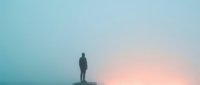 Silhouette of a man standing on a mountain peak at sunset, gazing at the horizon during golden hour. Suitable for motivational and inspirational content.