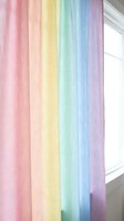 Pastel rainbow gradient curtain panel hanging by window creates soft colorful home decor accent for nursery bedroom living room interior design.