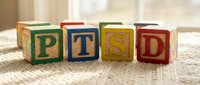 Colorful wooden blocks spelling PTSD arranged on neutral fabric surface, representing post-traumatic stress disorder awareness and mental health education.