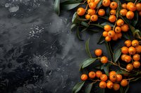 Fresh orange sea buckthorn berries with green leaves on dark stone background. Natural healthy superfood composition with copy space.