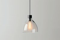 Clear glass dome pendant light with glowing vintage Edison bulb hanging against neutral wall, showcasing minimalist modern interior design style.