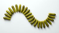 Pickled gherkins arranged in curved line on white background, isolated for food packaging, culinary design, recipe blogs, restaurant menus, and grocery advertising.