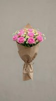 Pink roses bouquet wrapped in brown kraft paper with small white flowers on neutral background for romantic gifts and special occasions.