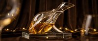 Elegant crystal whiskey decanter with amber liquid on wooden surface in warm atmospheric lighting for luxury bar and dining concepts.