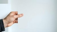Male hand with medium skin tone gesturing pinching or measuring small amount, wearing dark sleeve against white background for business, education, or instructional content.