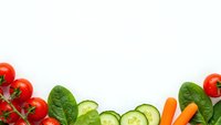 Fresh organic vegetables frame border with cherry tomatoes, cucumber slices, carrots and spinach leaves on white background for healthy cooking recipes.