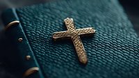 Golden ornate cross on dark teal leather texture background with shallow depth of field, creating spiritual and religious atmosphere for faith-based designs.