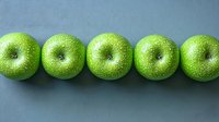 Fresh green apples in row with water drops on gray background, top view. Minimalist food composition showing organic produce for healthy eating.