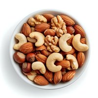 Mixed nuts in white ceramic bowl including almonds, cashews, walnuts and hazelnuts. Top view of healthy protein-rich snack on white background.