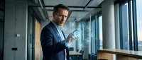 Professional businessman in suit interacting with holographic digital interface technology in modern office environment for business presentations.