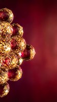 Golden faceted spheres with ruby red reflections floating on burgundy gradient background for luxury jewelry and gemstone design concepts.