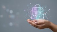 Caucasian woman's hand holding glowing shopping bag hologram with particles, representing digital commerce, online retail, and e-commerce technology solutions.