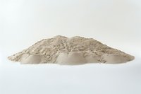 Pile of fine beige powder or flour isolated on white background, macro photography showing detailed texture and natural mineral composition.