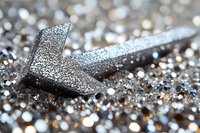 Metallic silver arrow symbol on glittering background with bokeh effect and shallow depth of field, modern business concept for direction and success.
