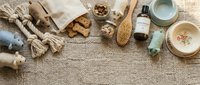 Flat lay composition of natural skincare and wellness products with ginger root, wooden brush, and organic ingredients on neutral linen fabric for beauty and spa branding.