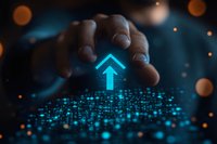 Glowing blue digital arrow pointing upward with male hand reaching above scattered light dots against dark background with bokeh effects creates futuristic atmosphere.