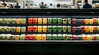 Fresh produce section in modern supermarket with colorful fruits and vegetables displayed on refrigerated shelves for healthy shopping experience.
