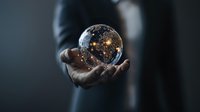 Glowing crystal ball with illuminated stars and galaxies floating above dark-skinned hands against moody background, mystical fortune telling concept.