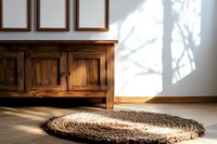 Round jute rug on wooden floor near vintage cabinet with dramatic window shadow casting natural light pattern on white wall. Interior design concept.
