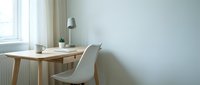 Minimalist workspace with wooden desk, white chair, and pendant lamp by window with natural light for home office or study room design.