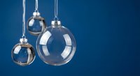 Clear glass Christmas ornaments hanging against deep blue background for holiday decorations and seasonal design projects.