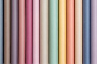 Colorful pastel pencils arranged in neat rows creating soft gradient pattern from beige to pink, mint, yellow and blue tones. Clean minimalist composition for design.
