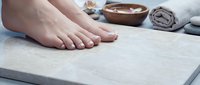 Woman feet on white towel at spa with wooden bowl and stones for relaxation massage therapy treatment. Pedicure and foot care concept for wellness center.